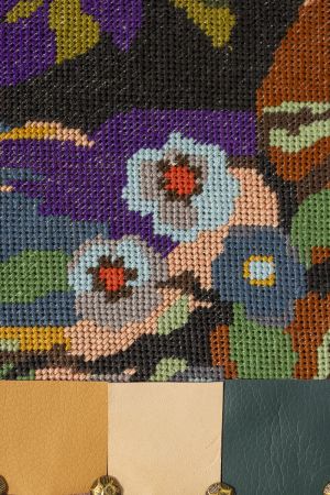 Close-up van geborduurd flamingotextiel met gestructureerde nepleren rand en stoffeernagels